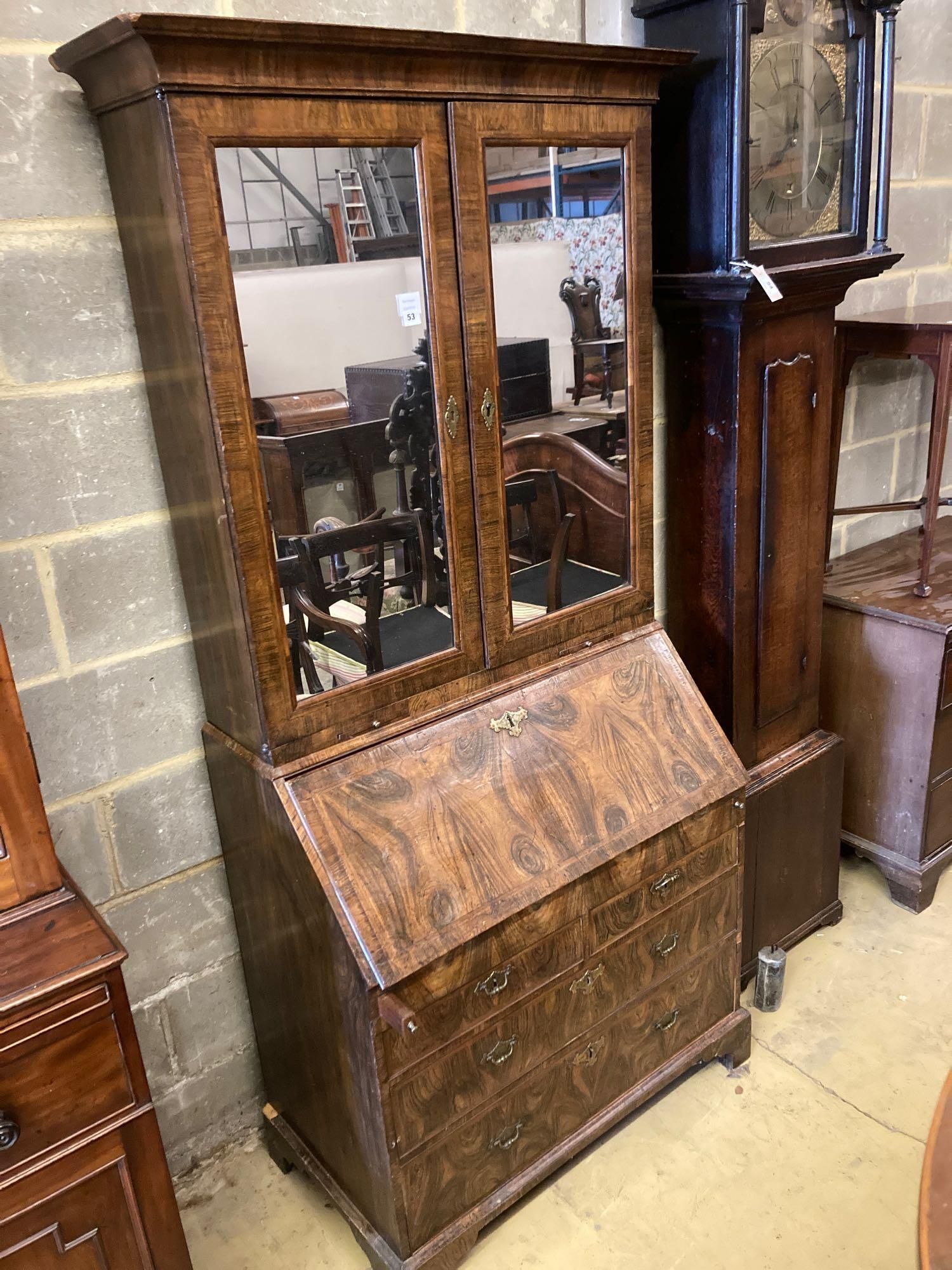 A mid 18th century style walnut bureau bookcase, with two mirrored doors enclosing a single adjustable shelf over candle slides and fal